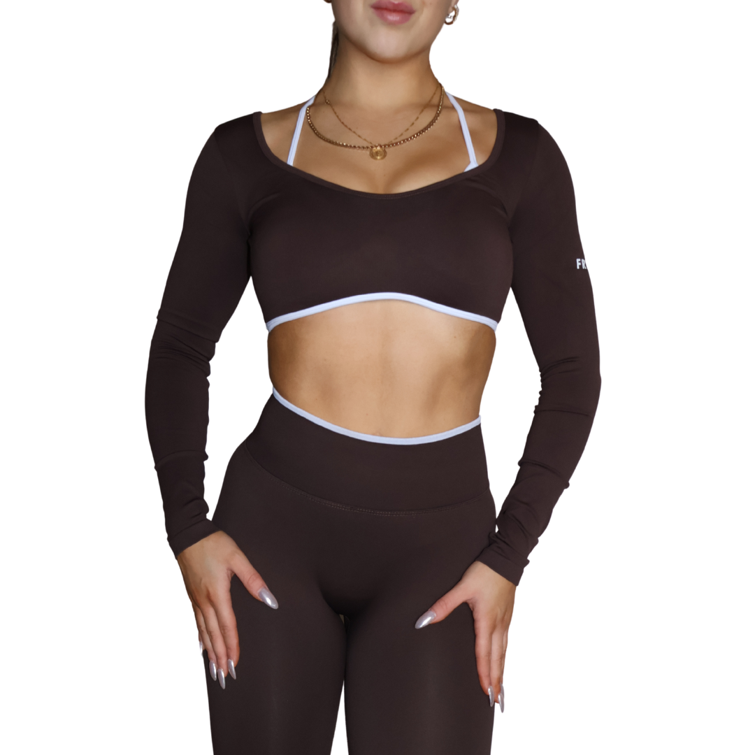 Person wearing a brown long-sleeve athletic top and leggings on a white background